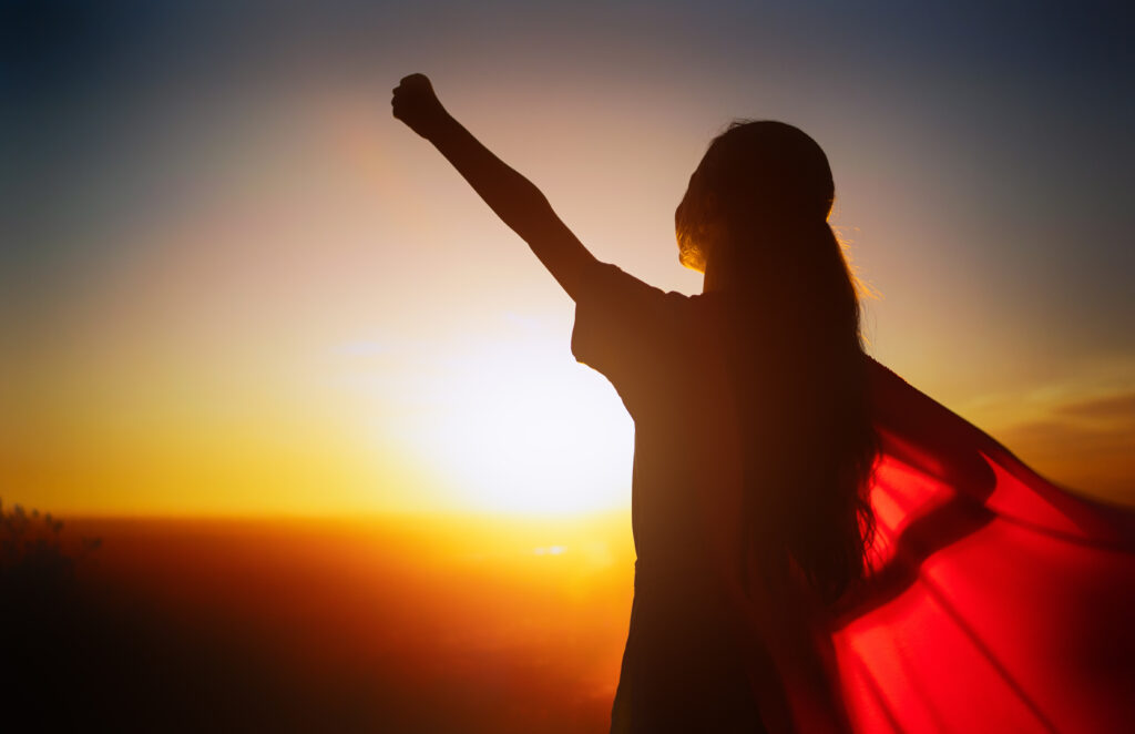 girl with a superman cape watching the sunset