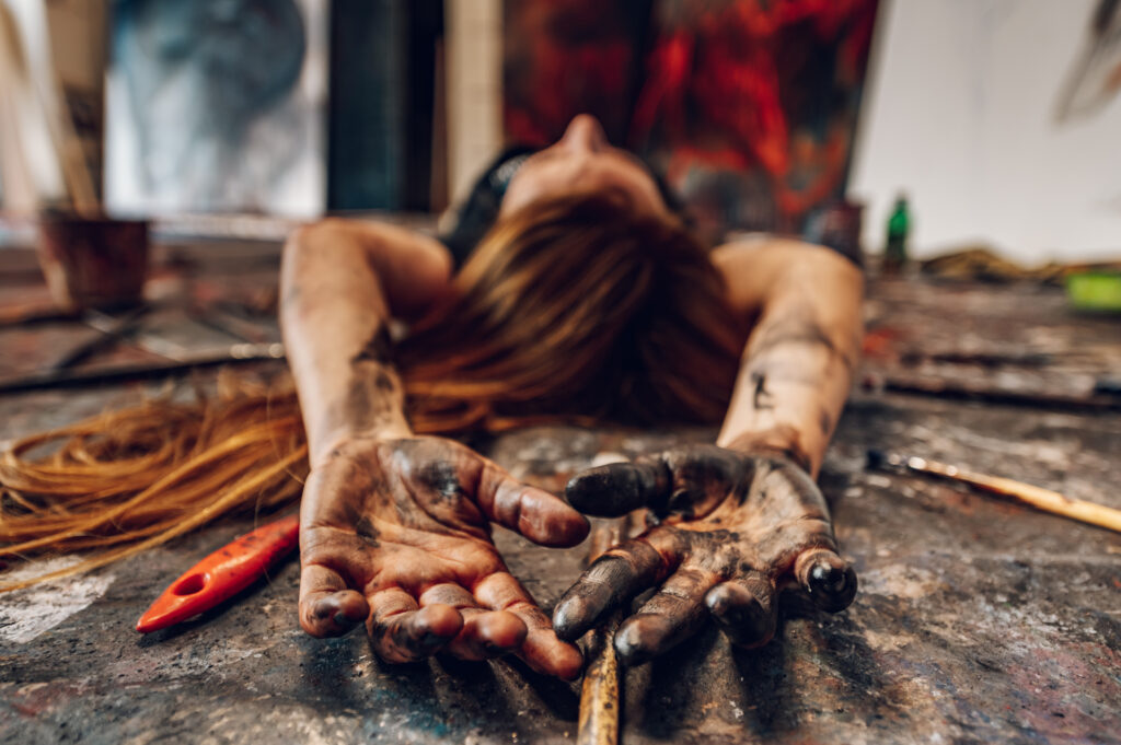 artist laying down with paint on her hands