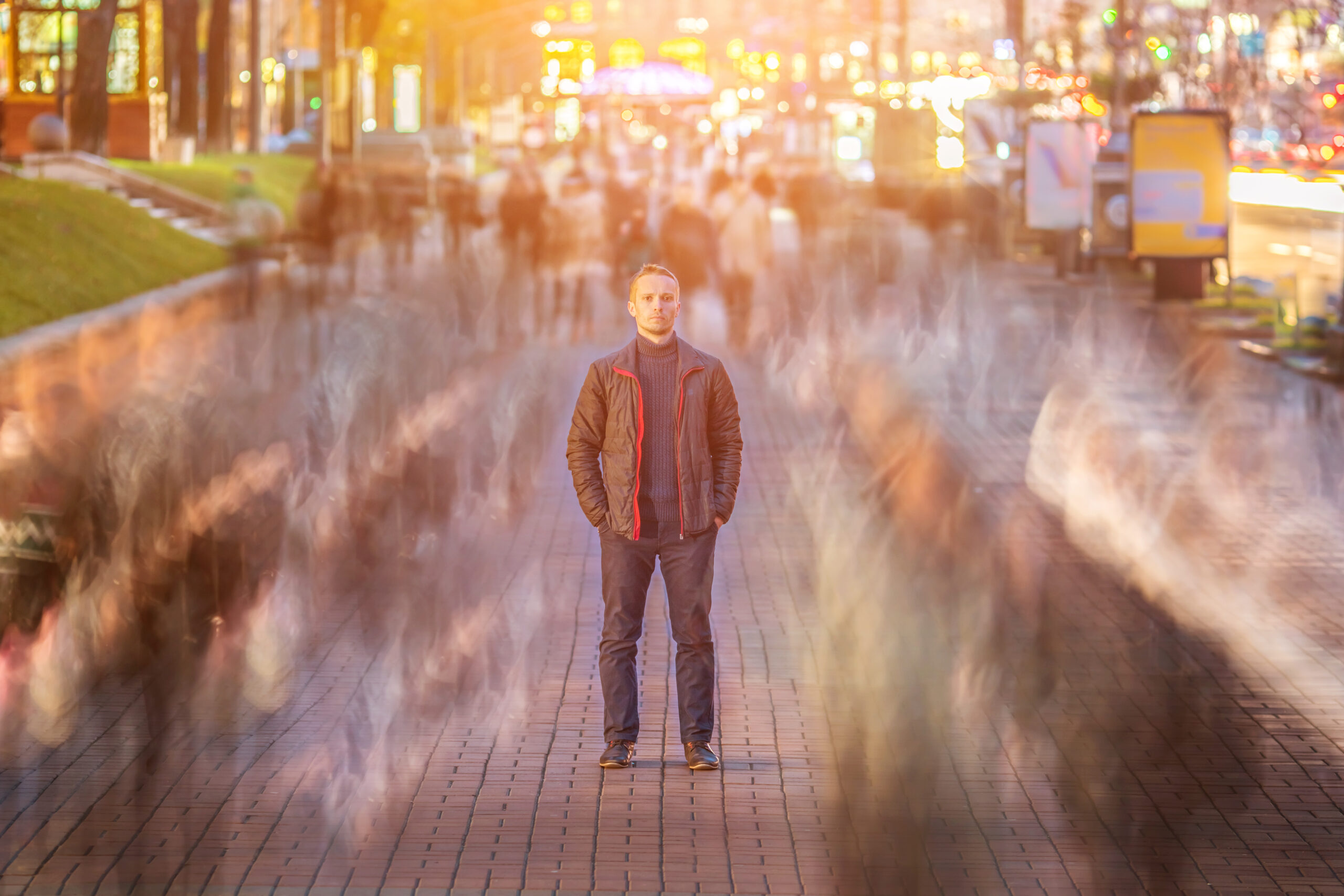 Man standing still amidst blurred crowd.