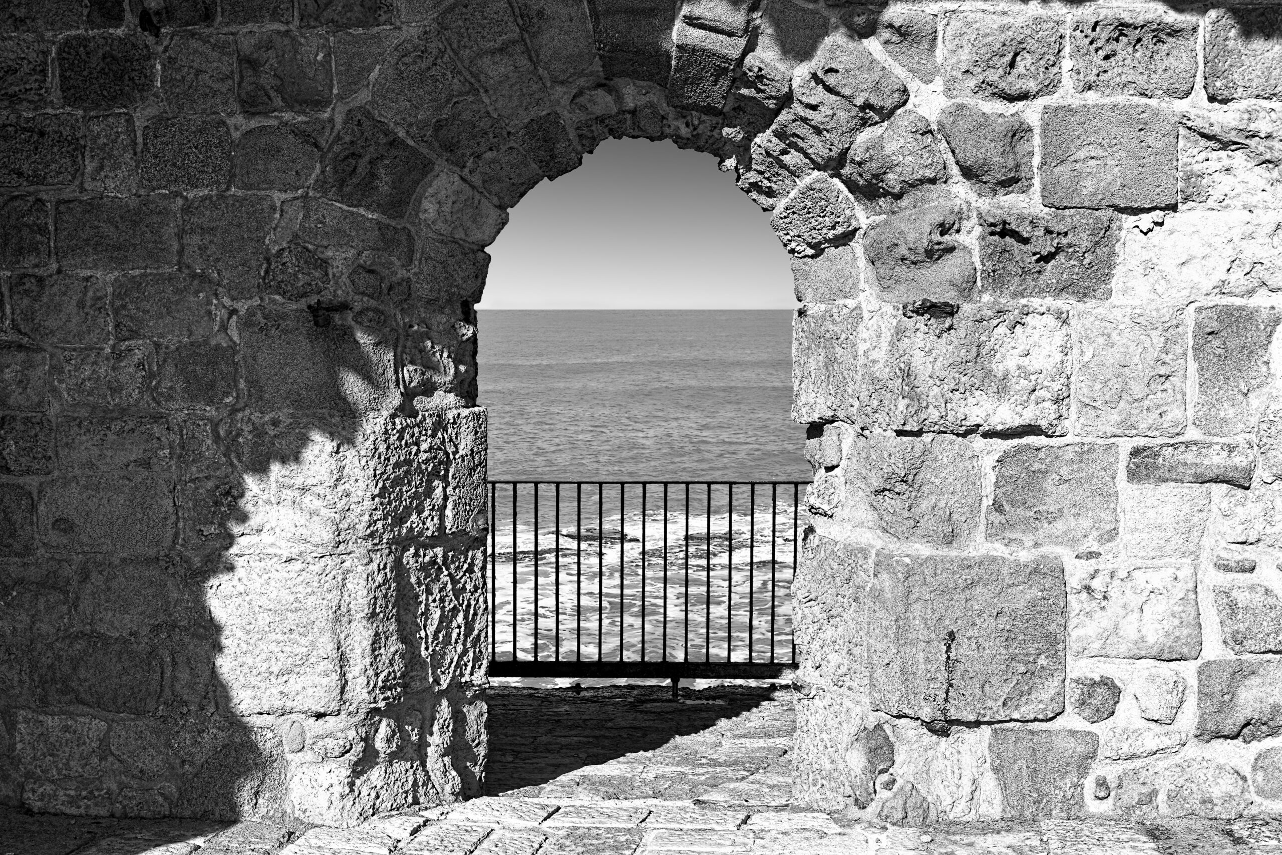 beach, sea, archway made of old brick, greyscale
